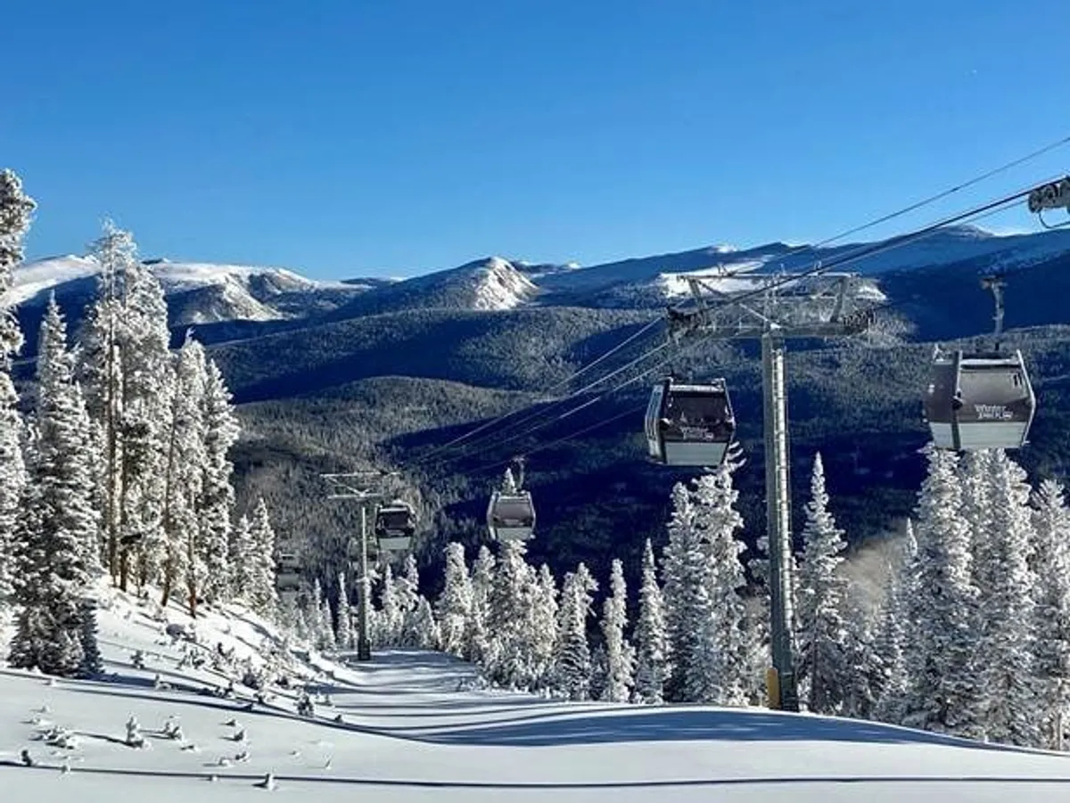 A dynamic exterior scene featuring a ski lift ascending through snow-laden trees, with a majestic mountain range in the background. The wintry adventure atmosphere is front and center, inviting guests to explore the natural beauty and seasonal activities of the area.
